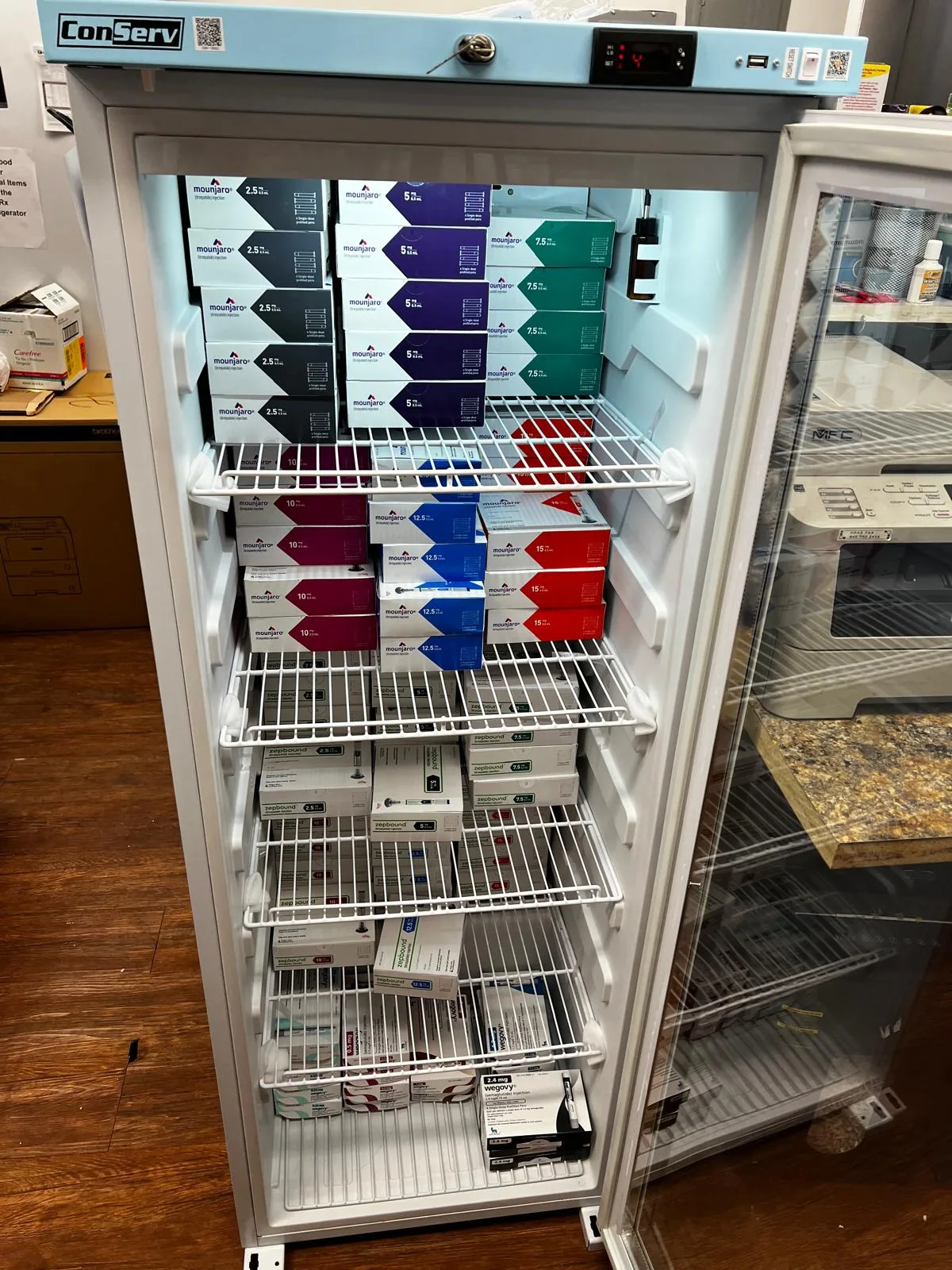 Pharmacy refrigerator stocked with Mounjaro, Zepbound, and Wegovy GLP-1 medications